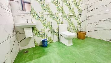 A bathroom with a toilet, sink, and green floor tiles.