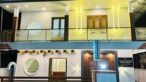 Un edificio de dos pisos con un balcón, un ventanal redondo y un letrero que indica Varkala Escape Beach Resort.