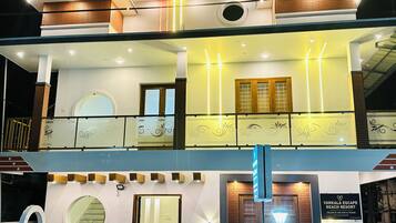 A two-story building with a balcony, a round window, and a sign for Varkala Escape Beach Resort.