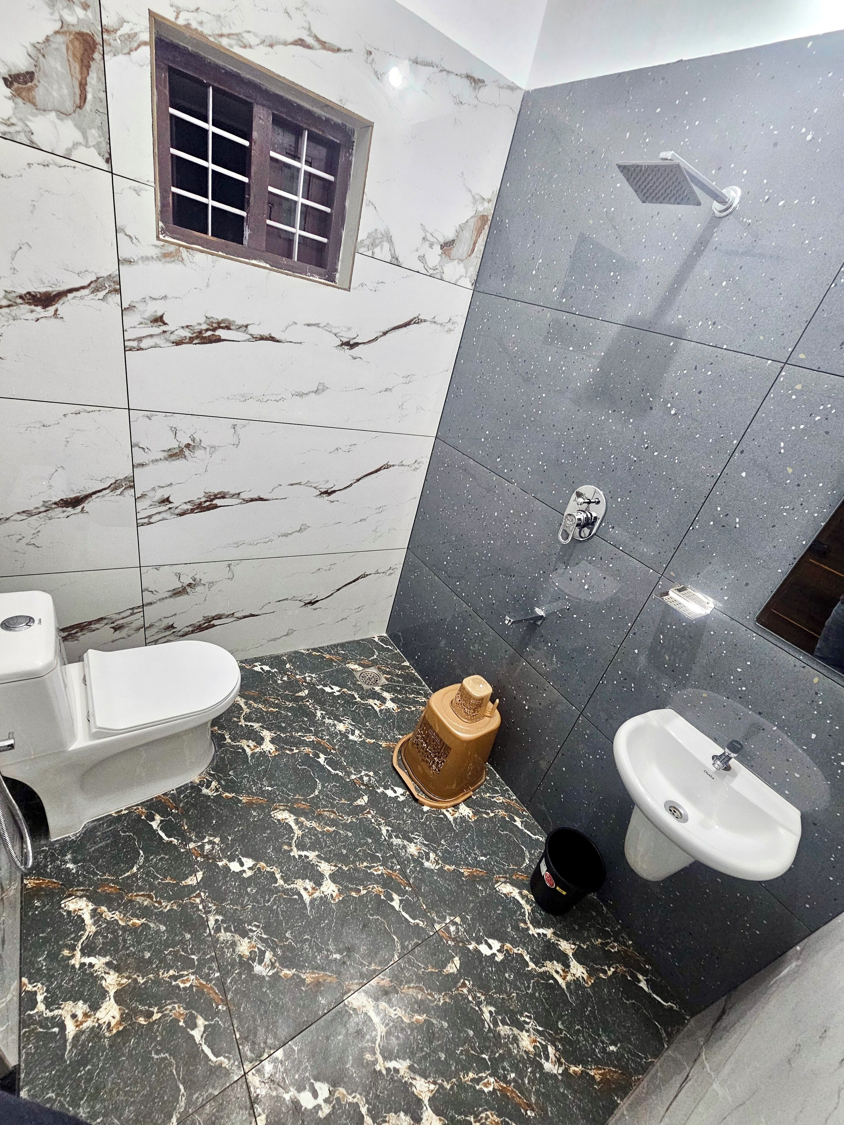 Un baño con inodoro, lavamanos, ducha y suelo de mármol.