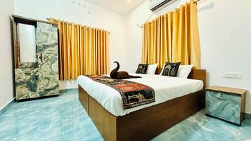 A hotel room with a marble floor, a bed with a patterned bedspread, a wooden headboard, and a nightstand.