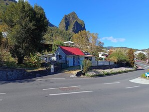 Un edificio con techo rojo, rodeado de vegetación y una montaña al fondo.