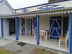 Un edificio con porche cubierto, paredes blancas y detalles azules.