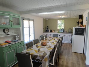 A compact kitchen with a dining area, featuring a table with a leaf-patterned tablecloth, a refrigerator, and a microwave.
