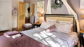 Een slaapkamer met een bed, een nachtkastje, een spiegel, een deur en een wand met bloemdecoratie.