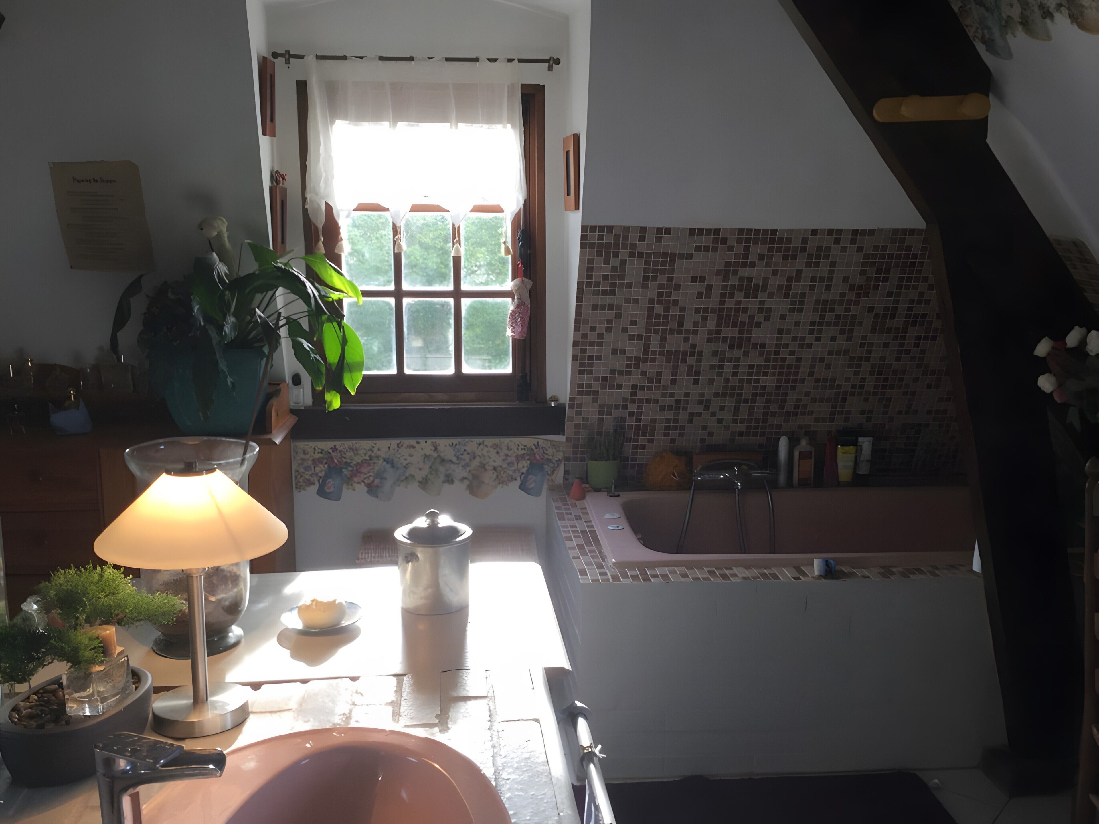 Une cuisine avec une fenêtre, un évier, une baignoire et une lampe.
