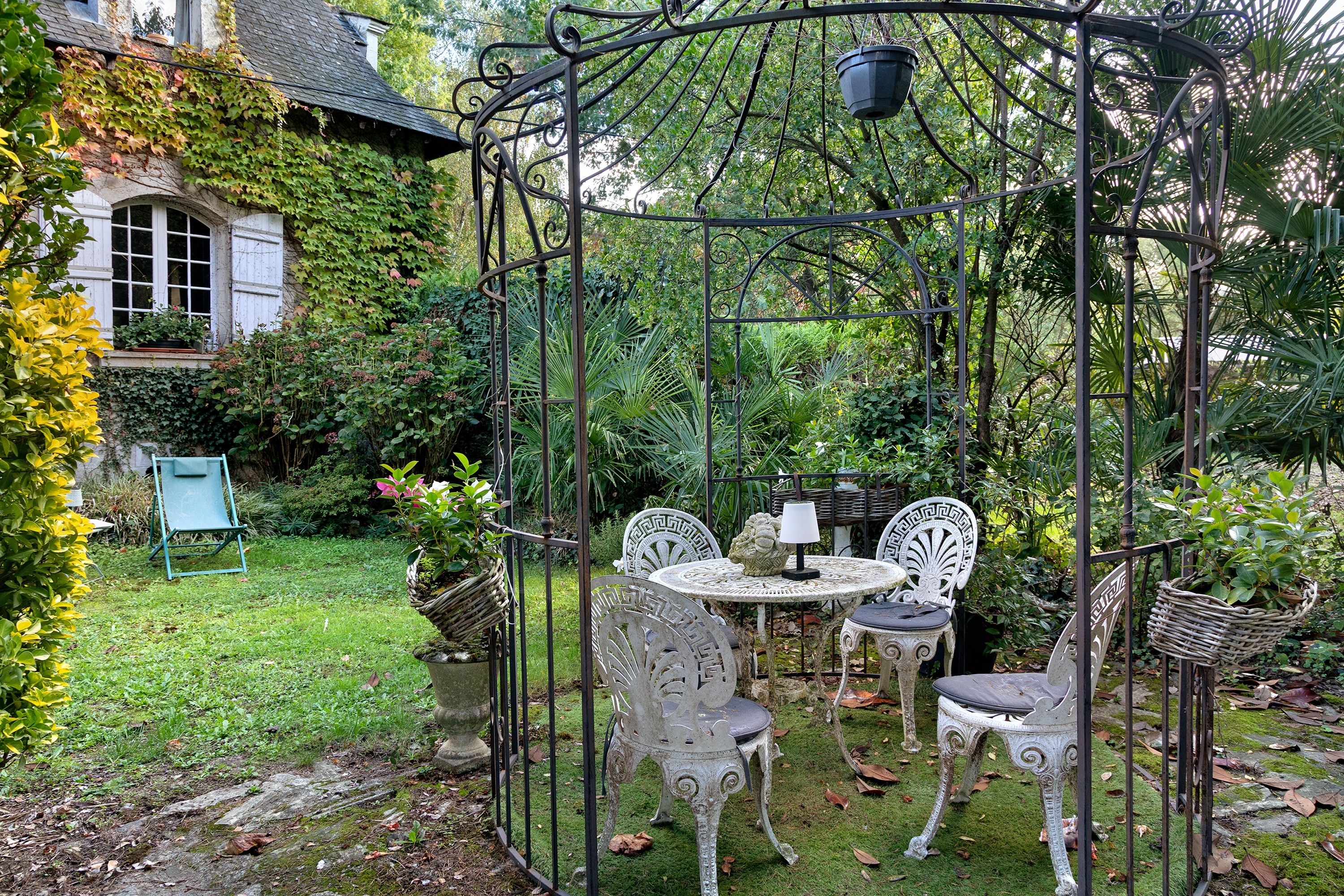Ein Garten mit einem Pavillon, zwei Stühlen, einem Tisch und einer hängenden Laterne.