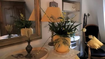 Una habitación con espejo, lámpara, silla y planta en una cómoda.