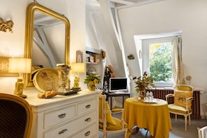 Une pièce avec un grand miroir, un bureau avec un ordinateur, une chaise et une fenêtre avec des rideaux.
