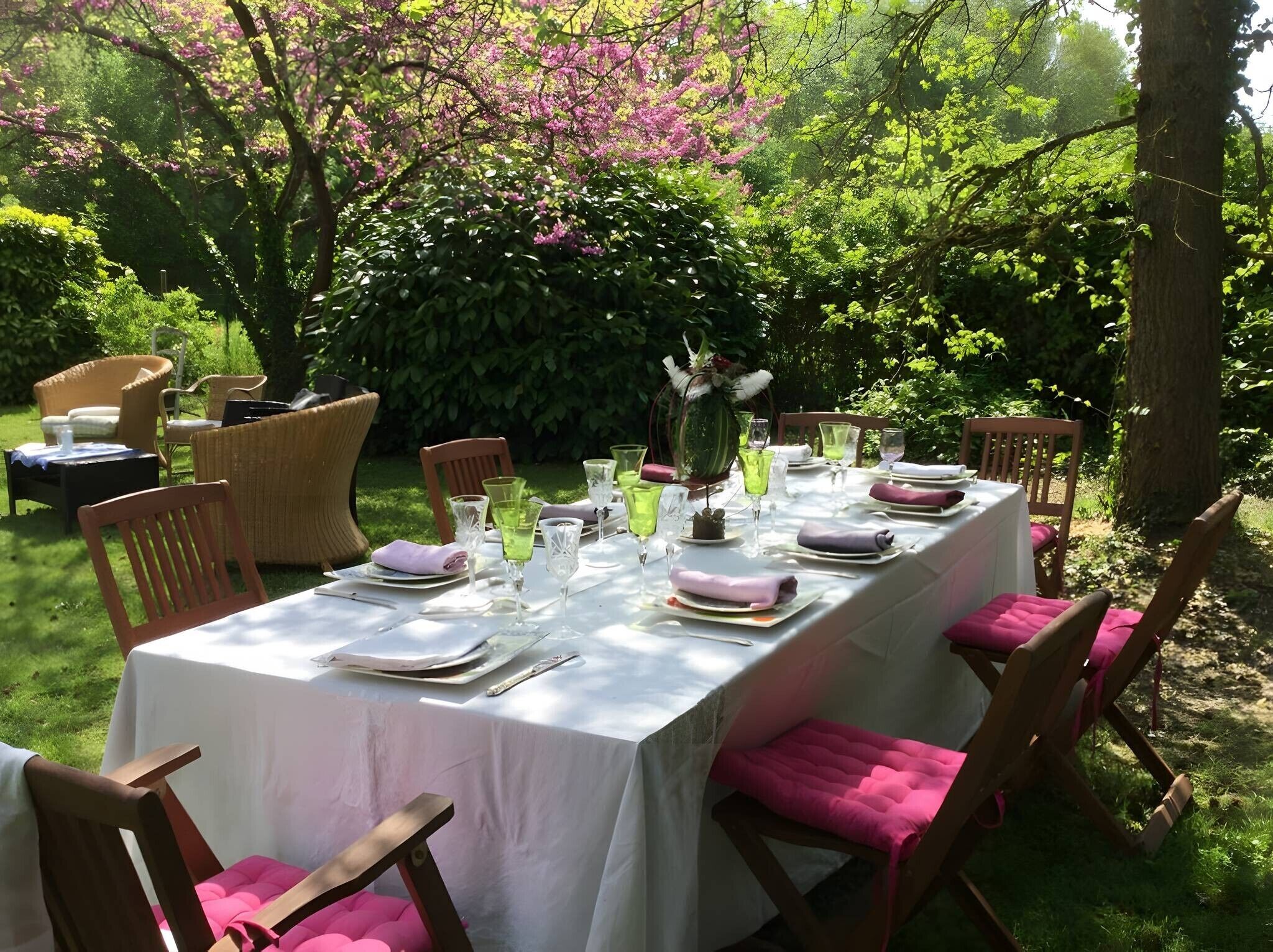 Un espacio de comedor al aire libre con una mesa preparada para una comida, rodeado de sillas con cojines.