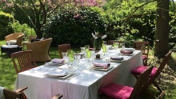 Un espacio de comedor al aire libre con una mesa preparada para una comida, rodeado de sillas con cojines.