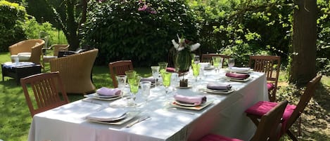Un espacio de comedor al aire libre con una mesa preparada para una comida, rodeado de sillas con cojines.