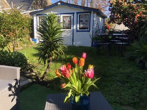 A small building with a sign that reads 'Bar à Huîtres' and a garden with a table and chairs. - Éole – Family House with Shared Terrace, Private Garden, and Wi-Fi (Cancale)