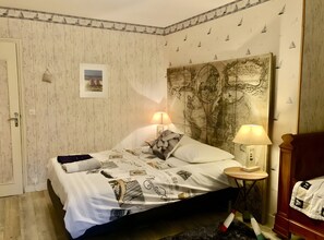 A bedroom with a bed, two bedside lamps, a map on the wall, and a door. - Éole – Family House with Shared Terrace, Private Garden, and Wi-Fi (Cancale)