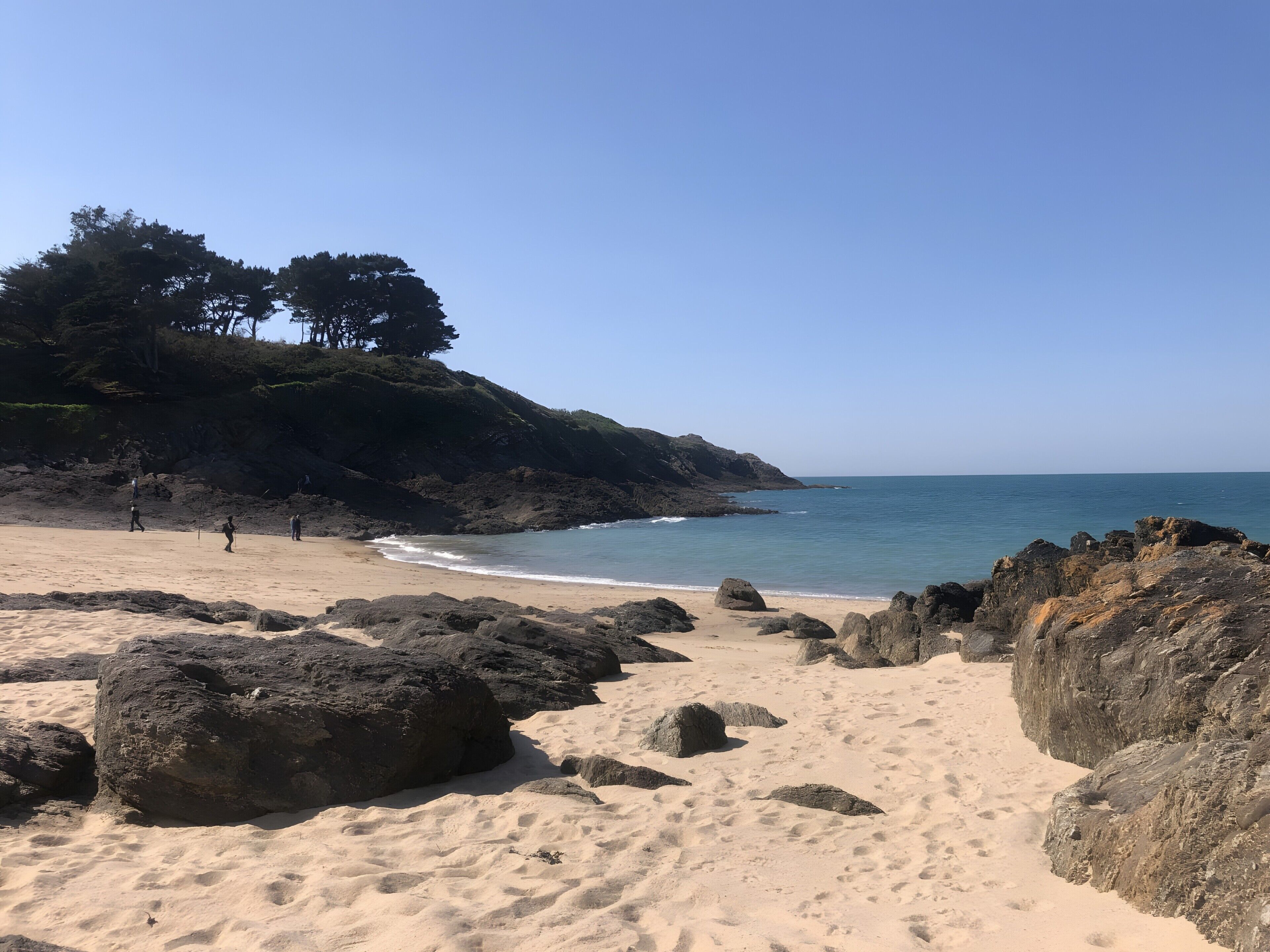 A beach with rocky terrain and a clear sky.
