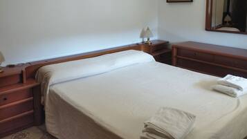 A neatly made bed with a white bedspread and two folded towels on the side.