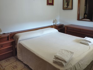 A neatly made bed with a white bedspread and two folded towels on the side. - Casa Vacanza da Nicola 2 (Cavaliere)
