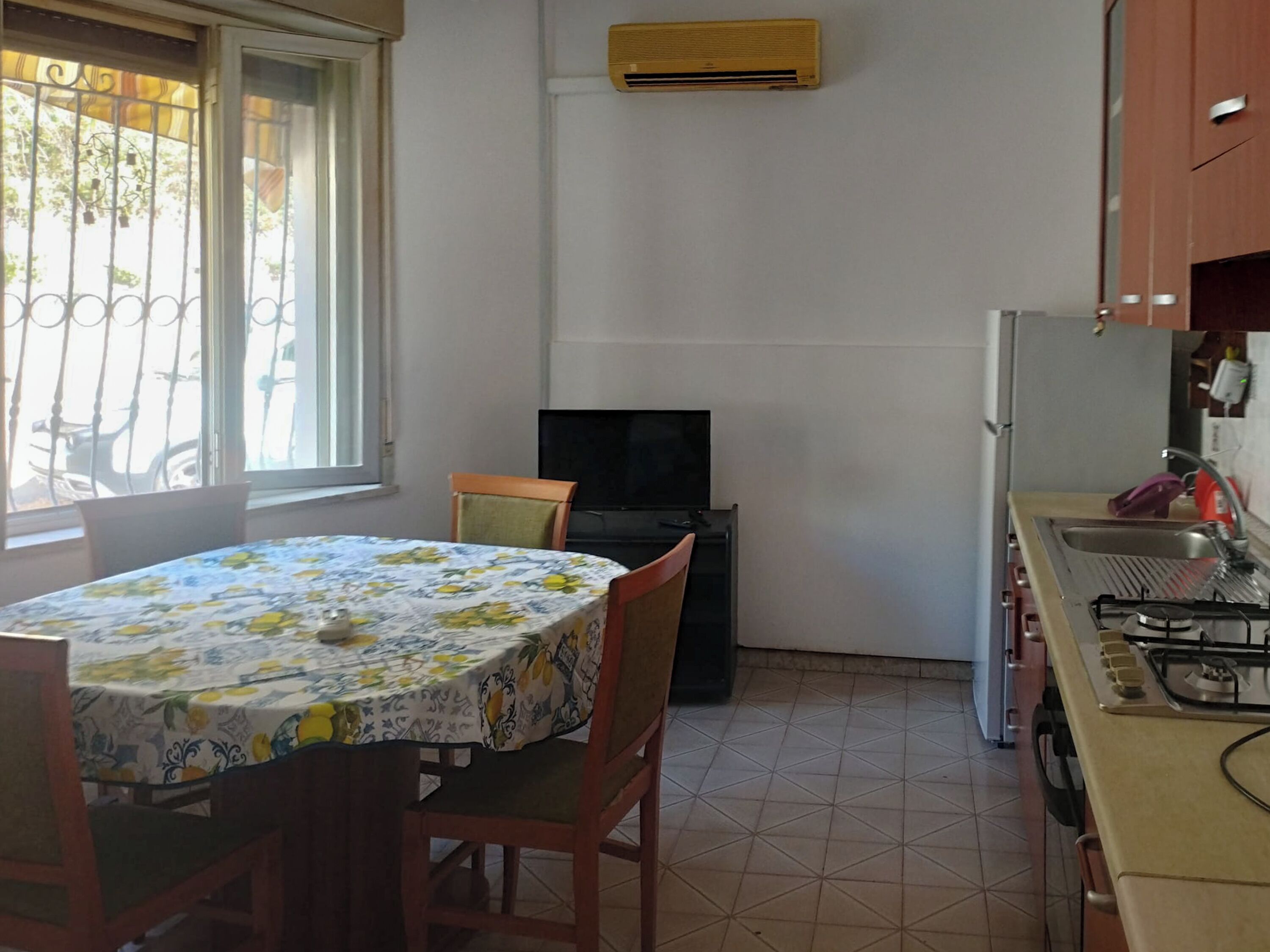 A compact kitchen with a dining table and chairs, a television, and a gas stove.