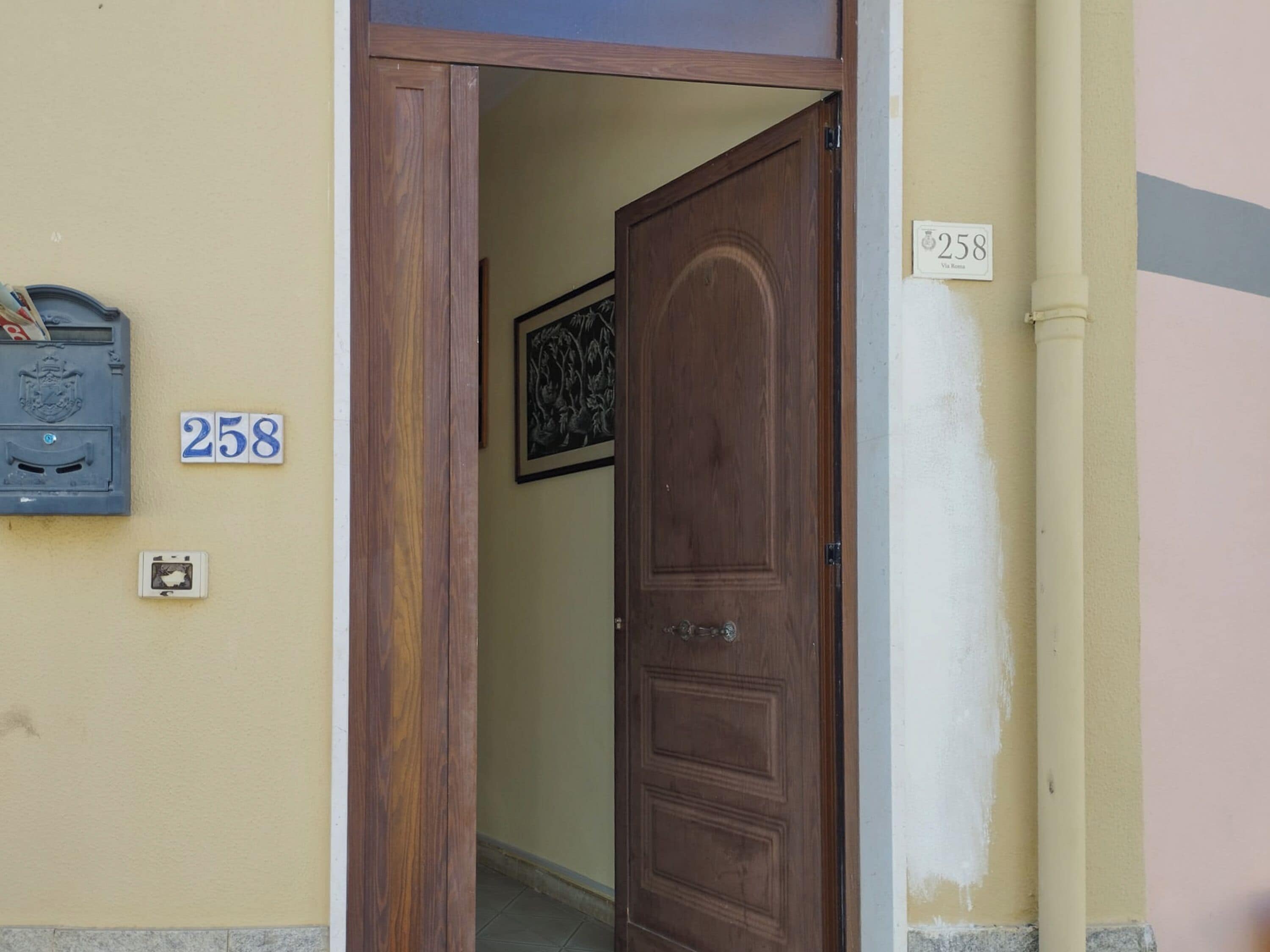 Une porte en bois portant le numéro « 258 » et une boîte aux lettres ornée d’un blason.