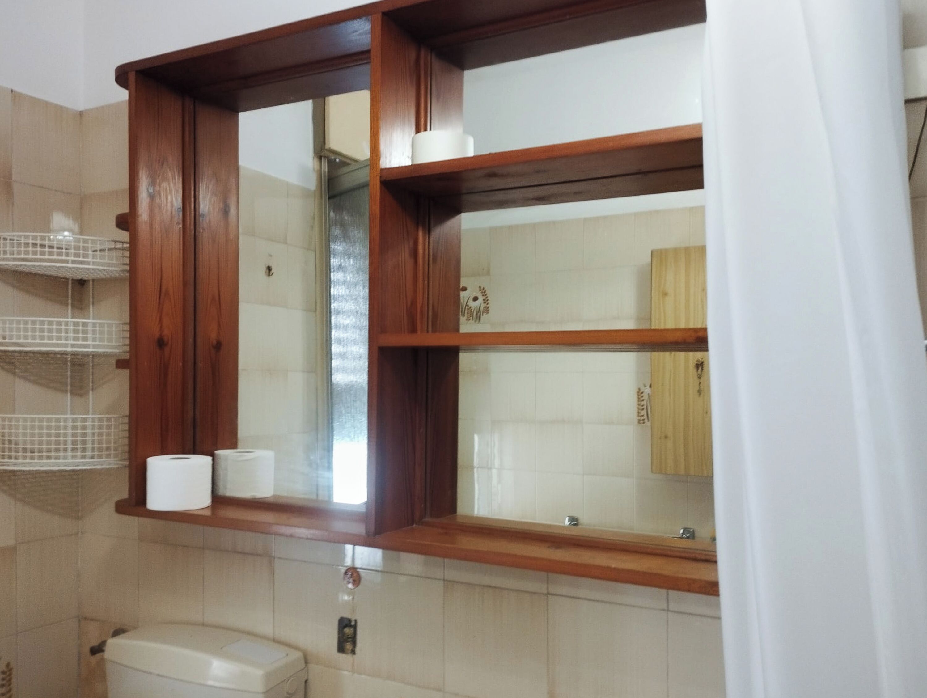 A bathroom with a wooden vanity, a toilet, and a mirror.