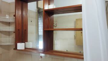A bathroom with a wooden vanity, a toilet, and a mirror.