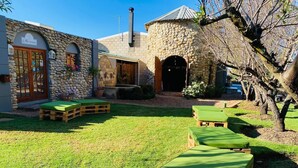 A stone building with a reception area, outdoor seating with green cushions, and a well-maintained lawn.