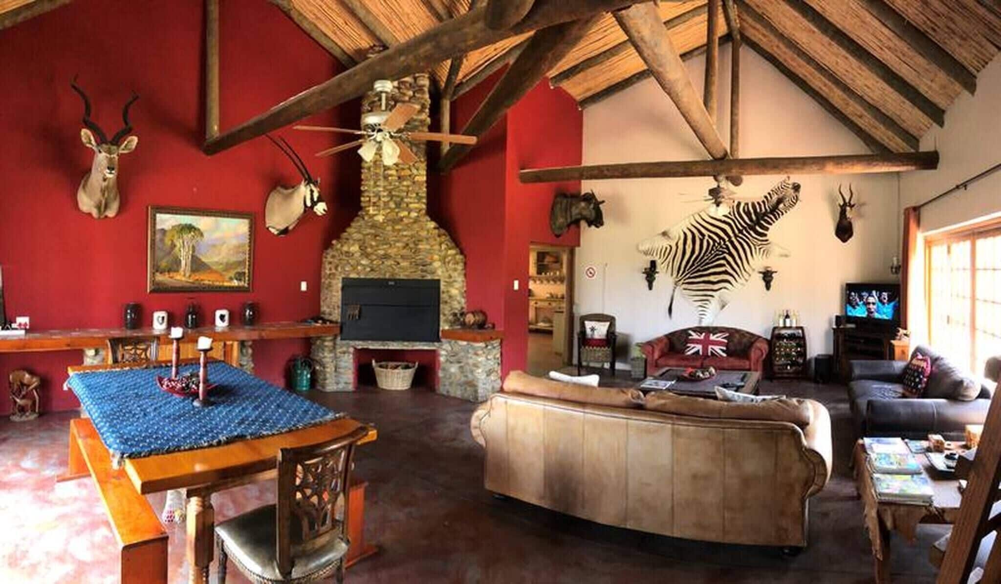 Un interior rústico con chimenea de piedra, techo de madera y un mural de cebra.