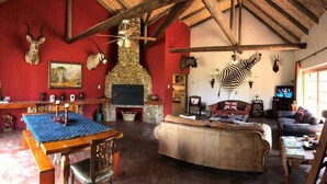 A rustic interior with a stone fireplace, a wooden ceiling, and a zebra mural. - Spacious Farmhouse Rental in Ladismith With Stunning Views (Ladismith)