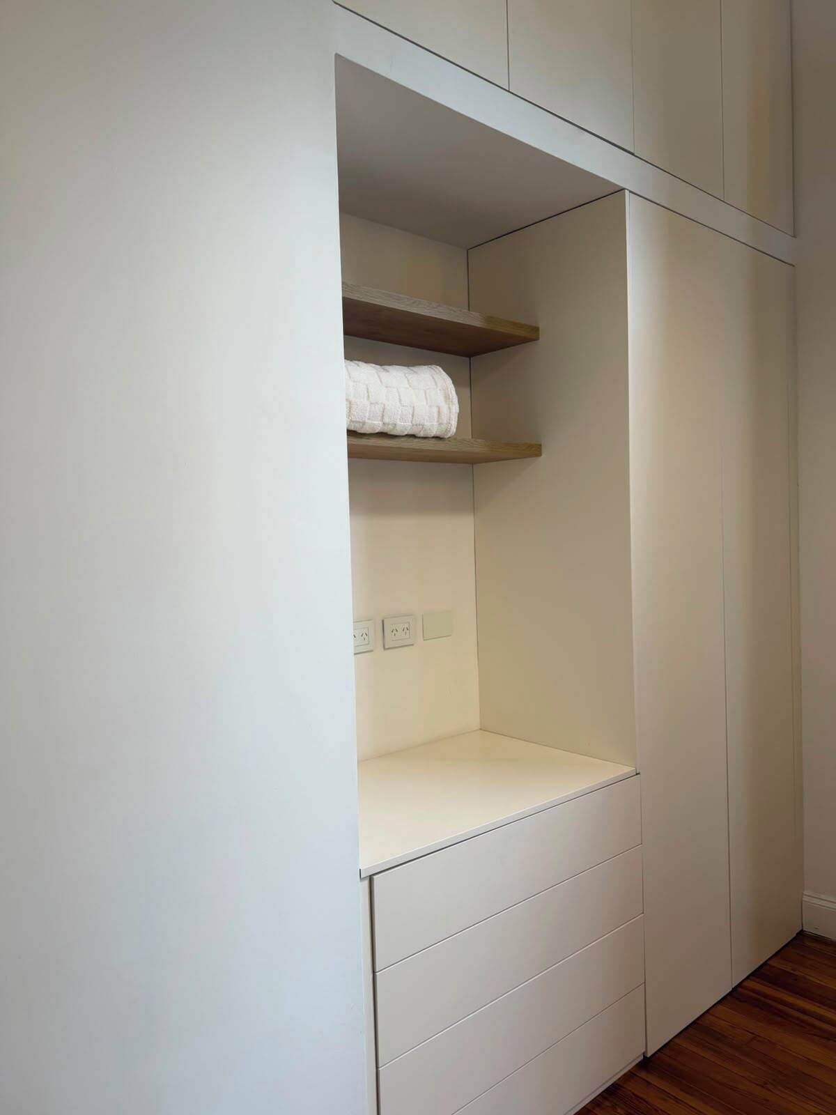 Guarda-roupa branco com prateleira suspensa e gavetas na parte inferior.