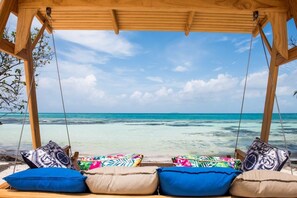 Un fauteuil suspendu en bois, agrémenté de coussins colorés, donnant sur une plage.