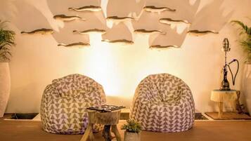 A cozy seating area with two bean bag chairs, a small wooden table, and a wall-mounted light fixture.