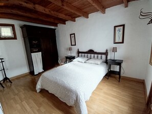 A bedroom with a wooden ceiling, a bed with white bedding, two bedside tables with lamps, a wardrobe, and a framed picture on the wall. - A House with Beautiful Sunrises (El rosario)