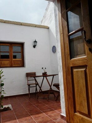 A patio with a wooden table and chairs, a window, and a door. - A House with Beautiful Sunrises (El rosario)