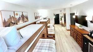 Et hotelværelse med seng, skrivebord, fjernsyn og kunst på væggen.