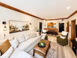 A living room with a sofa, a coffee table, and a dining area with chairs and a table. - 1020/22 | Stylish 2BR Villa | Sleeps 8 | Near Park City Skiing (Midway)