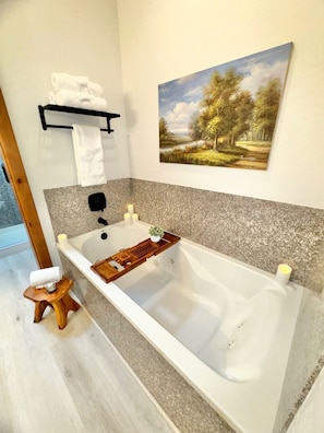 A modern bathroom with a freestanding bathtub, a wooden stool, a towel rack, and a painting of a landscape. - 1022 | Remodeled King Villa | Full Kitchen | Pool (Midway)