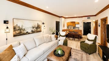 A living room with a sofa, a coffee table, and a dining area with chairs and a table.