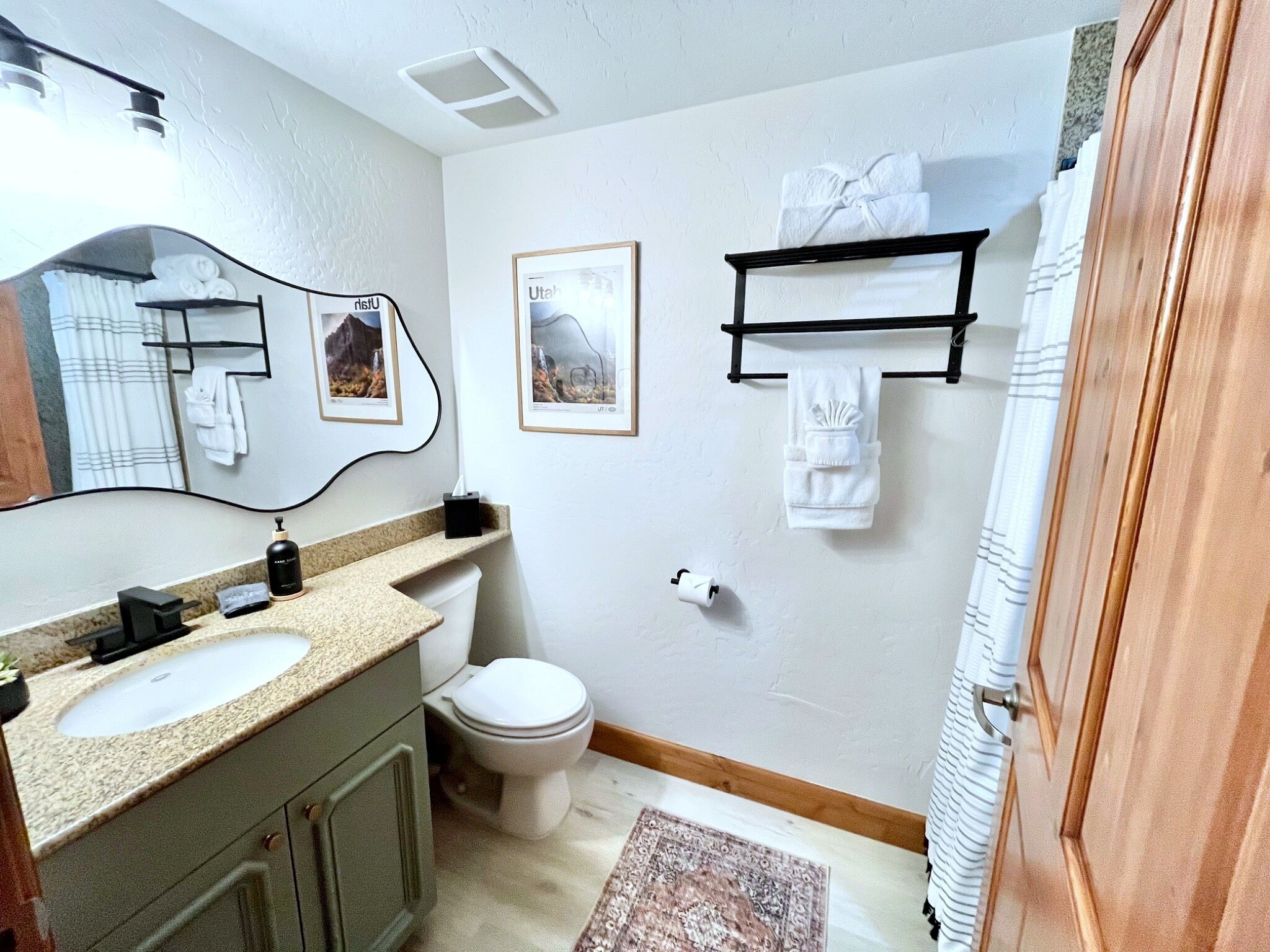 A bathroom with a double sink vanity, a toilet, a towel rack, and a framed picture on the wall.