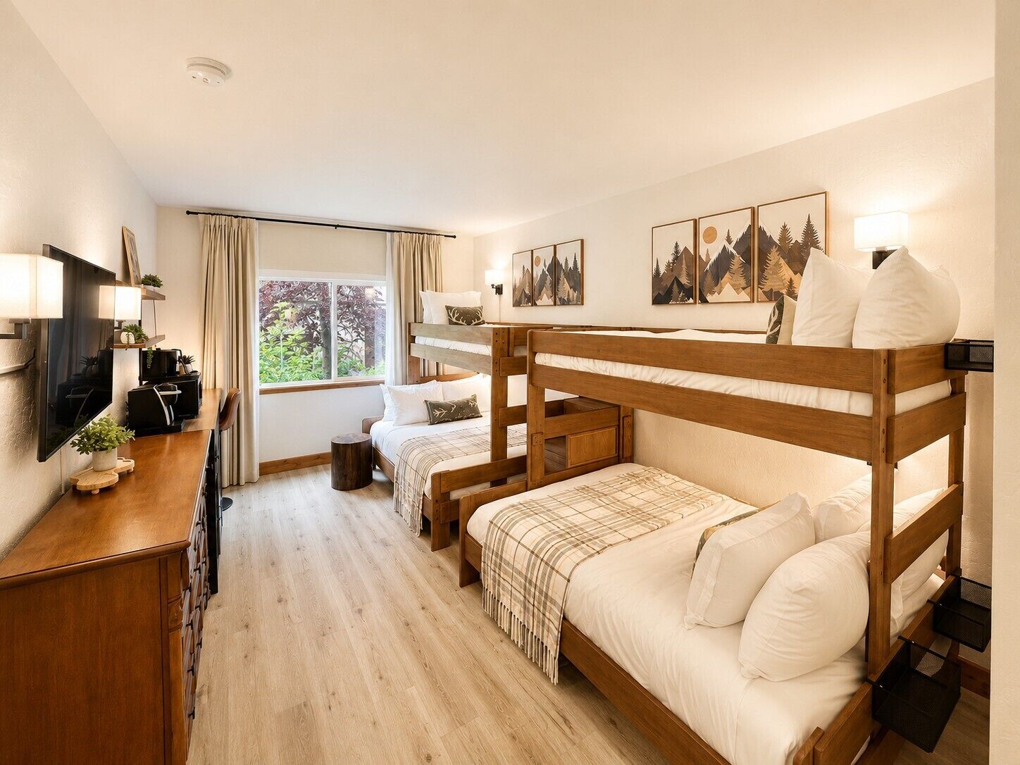 A bunk bed room with a desk, a television, and a window with curtains.