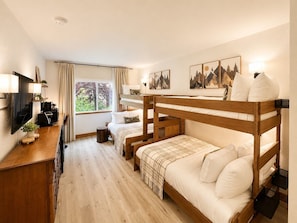 Camera con letto a castello, una scrivania, una televisione e una finestra con tende.