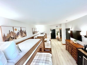 Una camera d'albergo con un letto, una scrivania, una televisione e opere d'arte alle pareti.