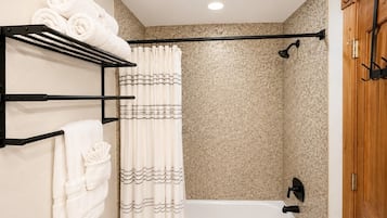 Ein Badezimmer mit Duschvorhang, einer Badewanne und einem Handtuchhalter mit gefalteten Handtüchern.