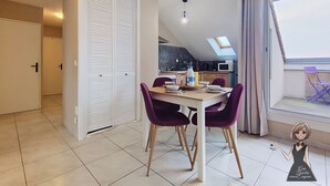 A dining area with a table, chairs, and a view of a kitchen and balcony. - The Tarbaise Canopy • Patio, tranquility & coziness (Tarbes)