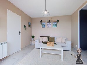 A modern living room with a white sofa, a coffee table, and a hanging light fixture.