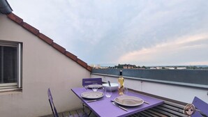 A dining table set with plates, cutlery, and a bottle on a balcony with a view. - The Tarbaise Canopy • Patio, tranquility & coziness (Tarbes)