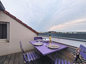 Een eettafel gedekt met borden, bestek en een fles op een balkon met uitzicht.