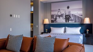Ein Hotelzimmer mit einem Bett, einem Kopfteil, einem Nachttisch, einer Lampe und einem Wandbild.