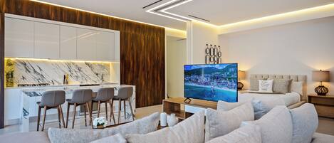 A modern hotel room with a living area, a dining space, and a bedroom.