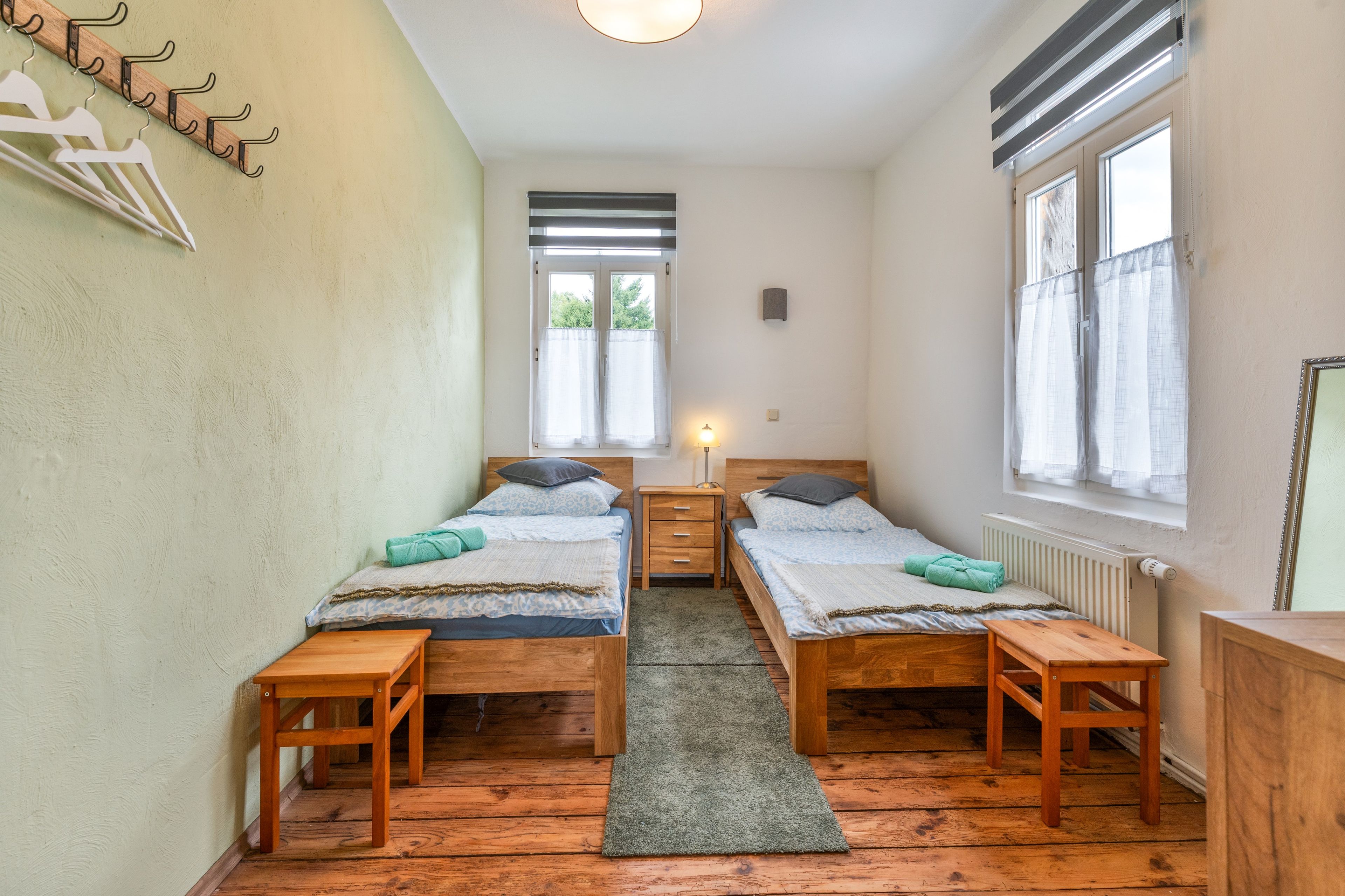 Un dormitorio con dos camas, suelo de madera, ventana y radiador.