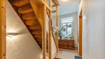 A wooden staircase leading to a landing with a view of a window and a plant.